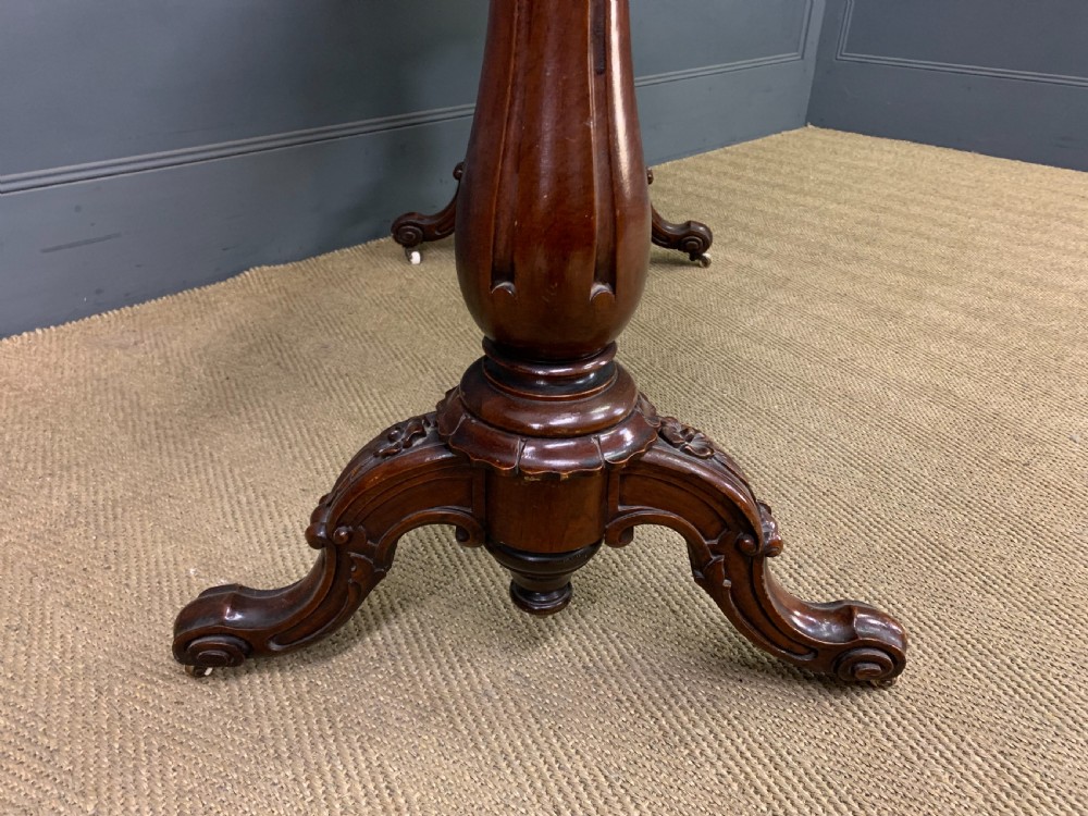 Victorian rosewood stretcher table featuring a serpentine top with figured grain, turned end supports, a carved central stretcher, and ceramic castors. View VIII