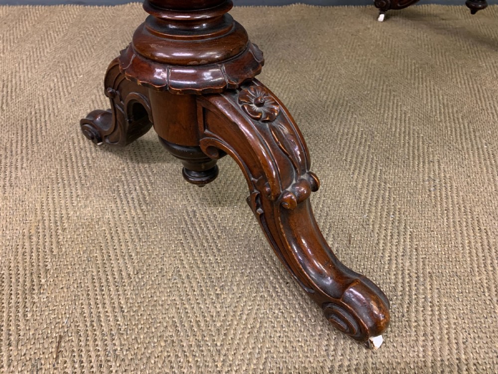Victorian rosewood stretcher table featuring a serpentine top with figured grain, turned end supports, a carved central stretcher, and ceramic castors. View IX