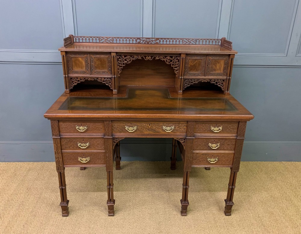 Victorian mahogany writing desk featuring a gallery superstructure with pierced fretwork, a brown leather inset surface, and multiple drawers with brass drop handles.