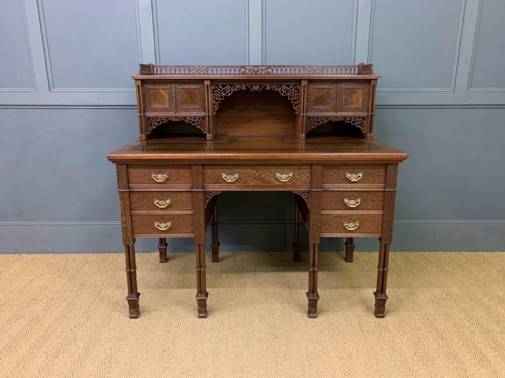 Victorian mahogany writing desk featuring a gallery superstructure with pierced fretwork, a brown leather inset surface, and multiple drawers with brass drop handles. View II
