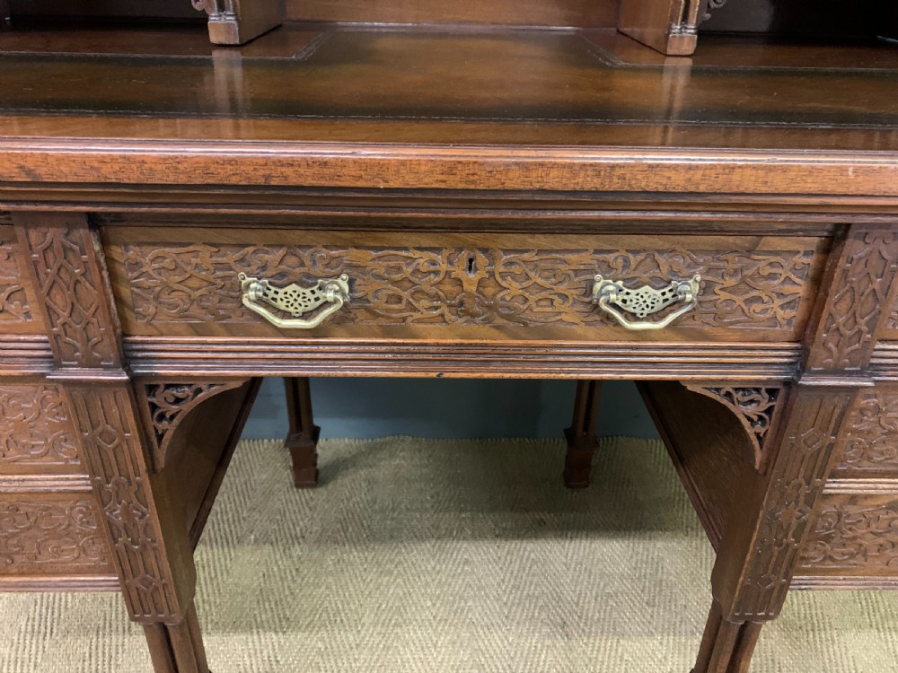Victorian mahogany writing desk featuring a gallery superstructure with pierced fretwork, a brown leather inset surface, and multiple drawers with brass drop handles. View VII