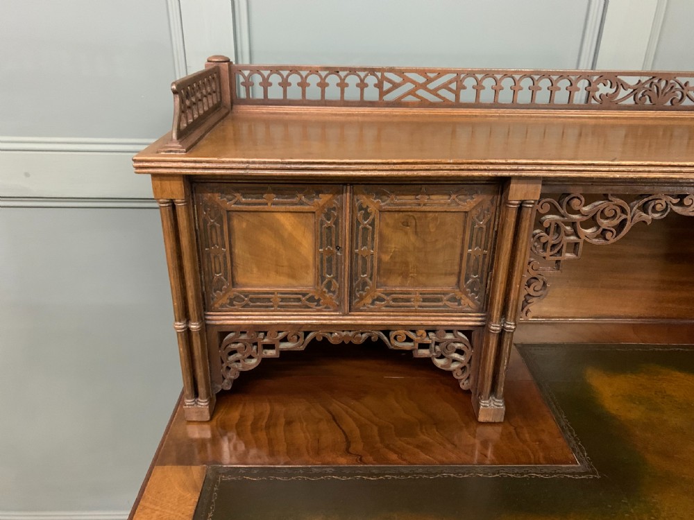 Victorian mahogany writing desk featuring a gallery superstructure with pierced fretwork, a brown leather inset surface, and multiple drawers with brass drop handles. View IX