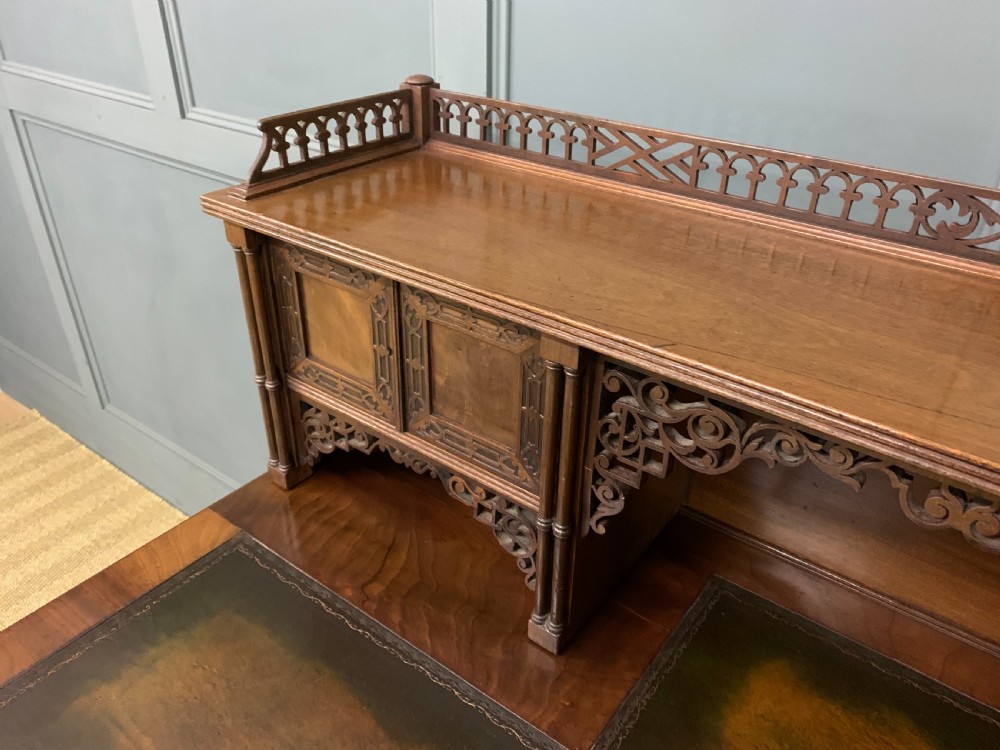 Victorian mahogany writing desk featuring a gallery superstructure with pierced fretwork, a brown leather inset surface, and multiple drawers with brass drop handles. View X