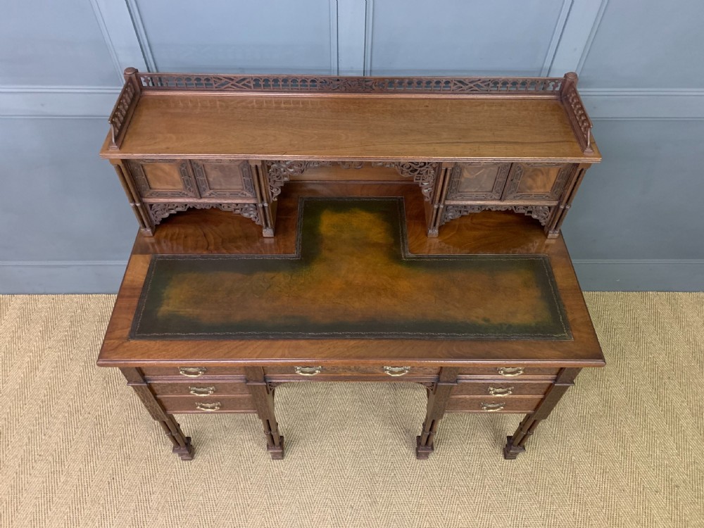 Victorian mahogany writing desk featuring a gallery superstructure with pierced fretwork, a brown leather inset surface, and multiple drawers with brass drop handles. View XII