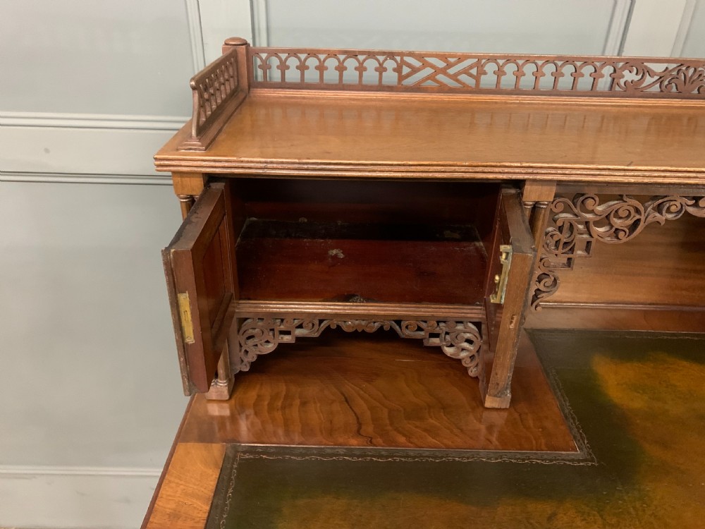 Victorian mahogany writing desk featuring a gallery superstructure with pierced fretwork, a brown leather inset surface, and multiple drawers with brass drop handles. View XIV