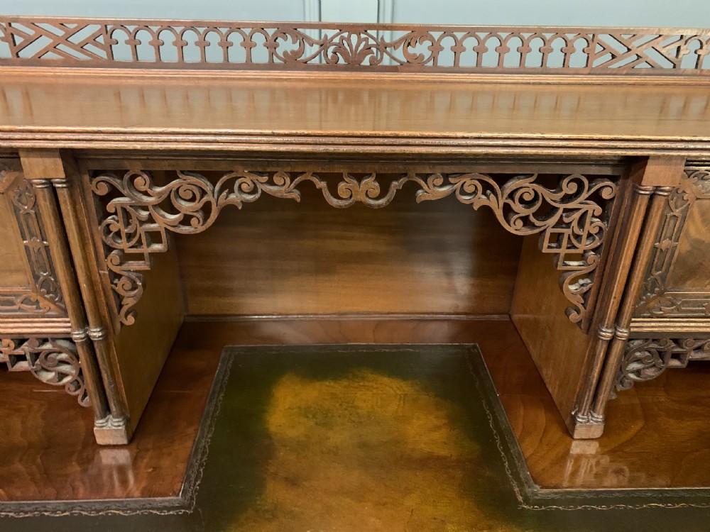 Victorian mahogany writing desk featuring a gallery superstructure with pierced fretwork, a brown leather inset surface, and multiple drawers with brass drop handles. View XVI