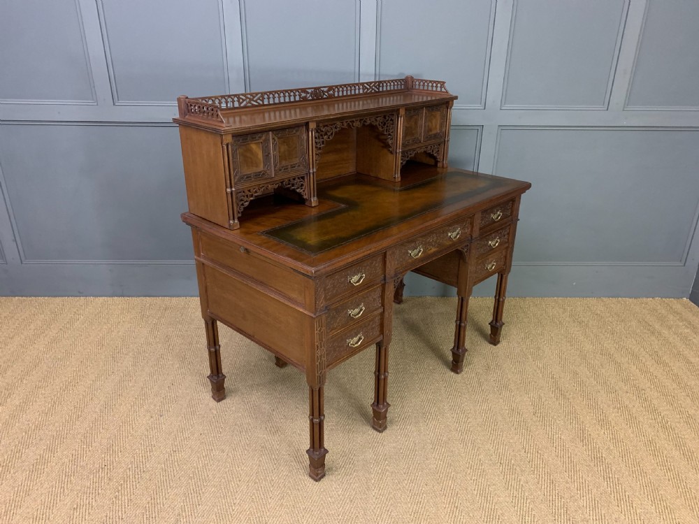 Victorian mahogany writing desk featuring a gallery superstructure with pierced fretwork, a brown leather inset surface, and multiple drawers with brass drop handles. View XIX