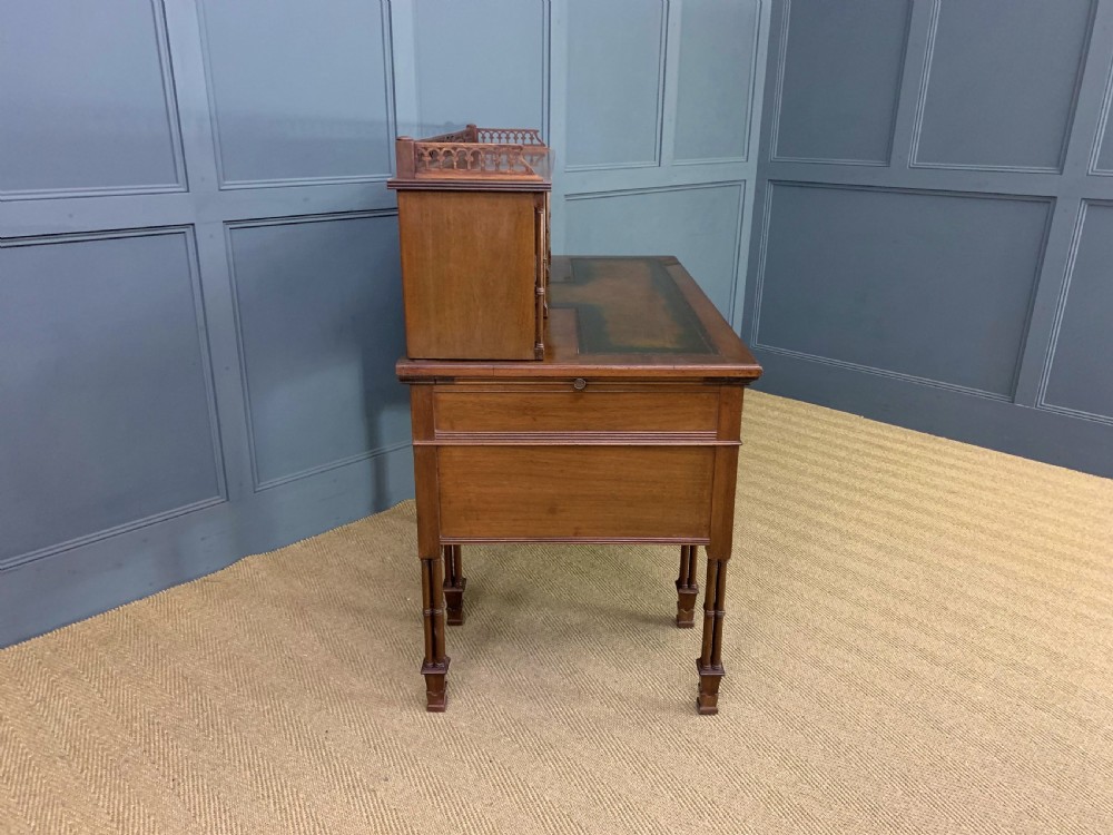 Victorian mahogany writing desk featuring a gallery superstructure with pierced fretwork, a brown leather inset surface, and multiple drawers with brass drop handles. View XX