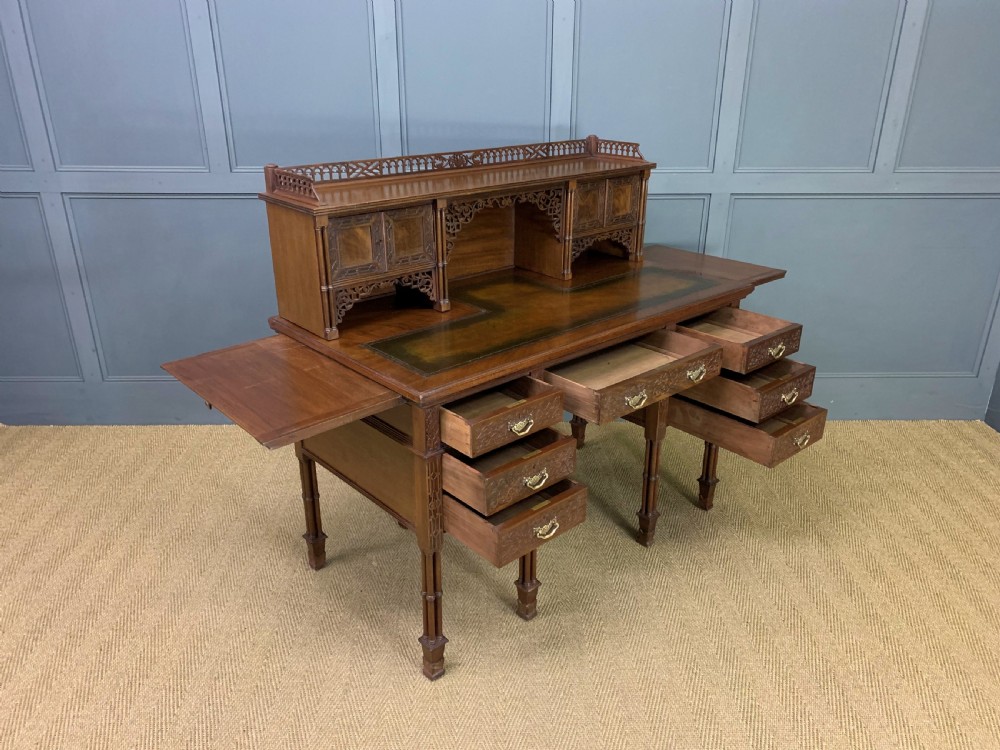 Victorian mahogany writing desk featuring a gallery superstructure with pierced fretwork, a brown leather inset surface, and multiple drawers with brass drop handles. View XXII