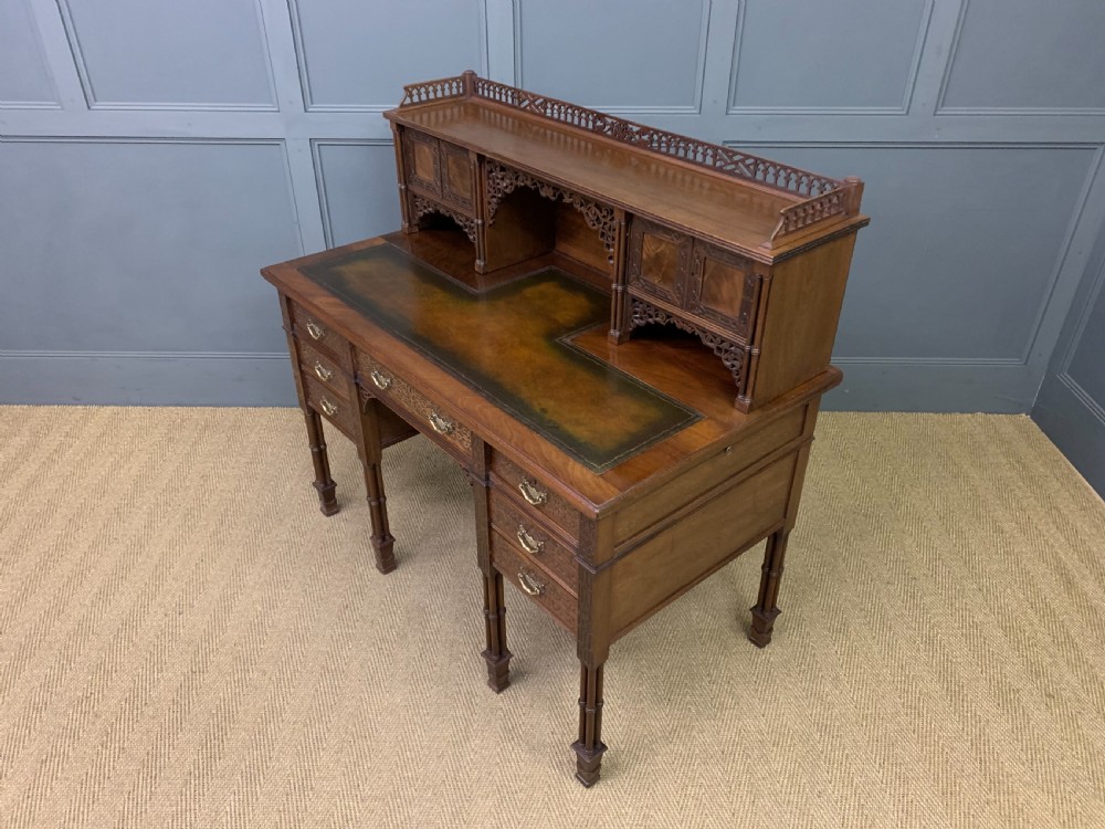 Victorian mahogany writing desk featuring a gallery superstructure with pierced fretwork, a brown leather inset surface, and multiple drawers with brass drop handles. View XXIV