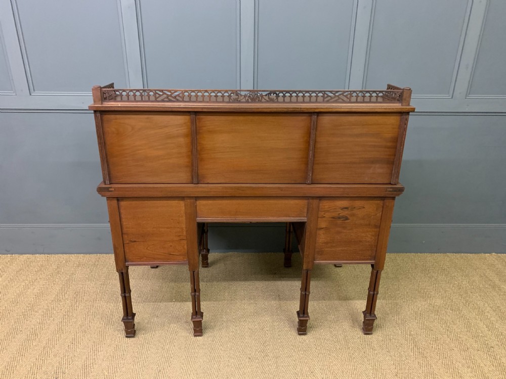 Victorian mahogany writing desk featuring a gallery superstructure with pierced fretwork, a brown leather inset surface, and multiple drawers with brass drop handles. View XXV