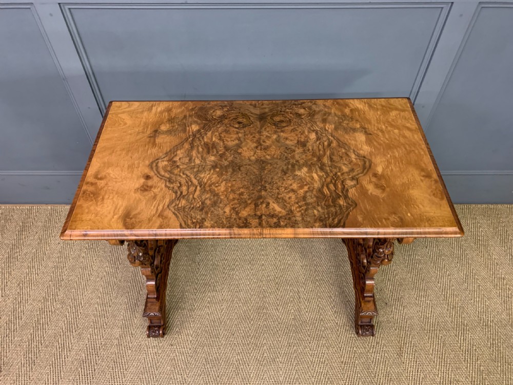 An antique Victorian rectangular table crafted from figured burr walnut veneer with intricately carved trestle supports. View IV