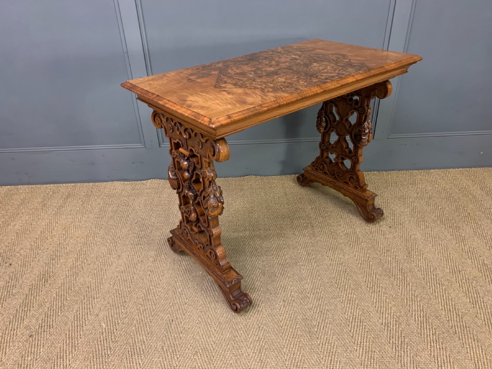 An antique Victorian rectangular table crafted from figured burr walnut veneer with intricately carved trestle supports. View V