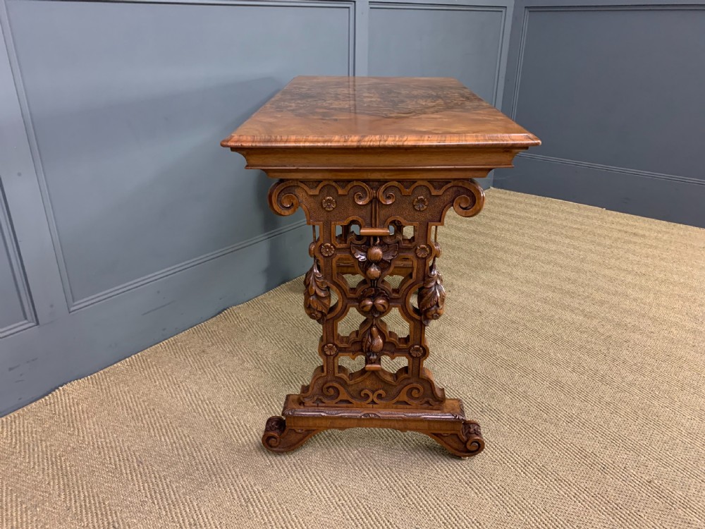 An antique Victorian rectangular table crafted from figured burr walnut veneer with intricately carved trestle supports. View VI