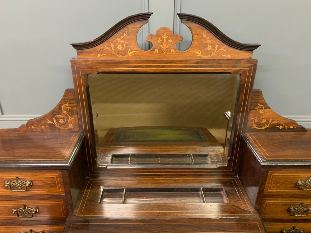 An antique rosewood bonheur du jour writing desk featuring intricate marquetry inlays, a central mirror, green leather writing top, and tapered legs on brass castors. View III