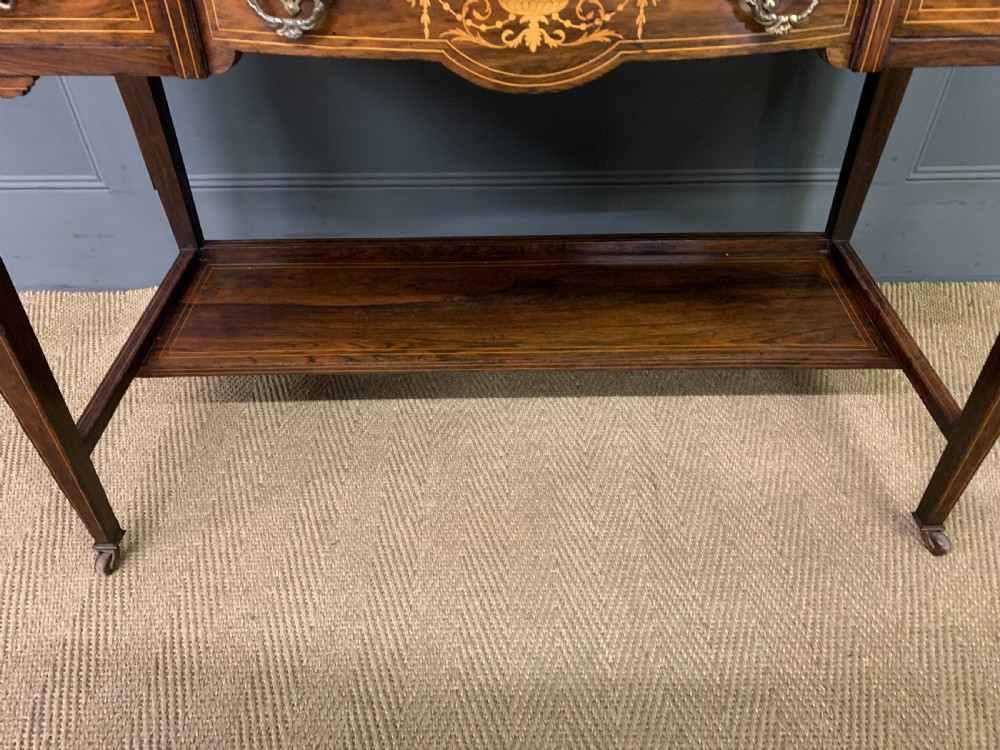An antique rosewood bonheur du jour writing desk featuring intricate marquetry inlays, a central mirror, green leather writing top, and tapered legs on brass castors. View VI