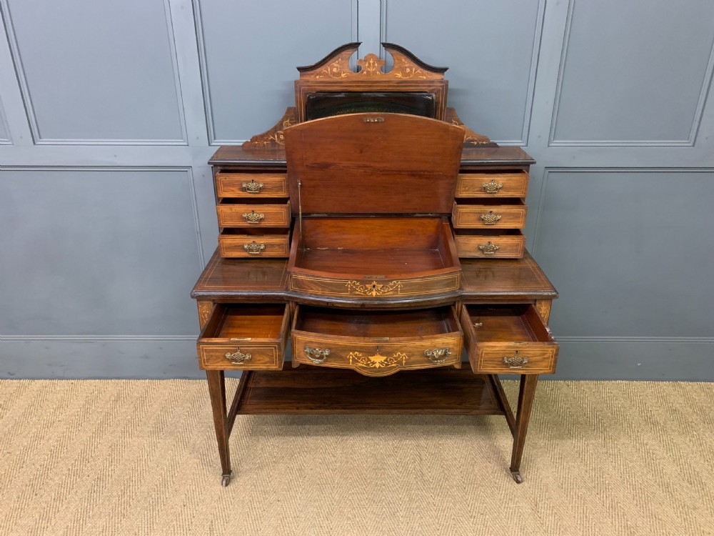 An antique rosewood bonheur du jour writing desk featuring intricate marquetry inlays, a central mirror, green leather writing top, and tapered legs on brass castors. View XII