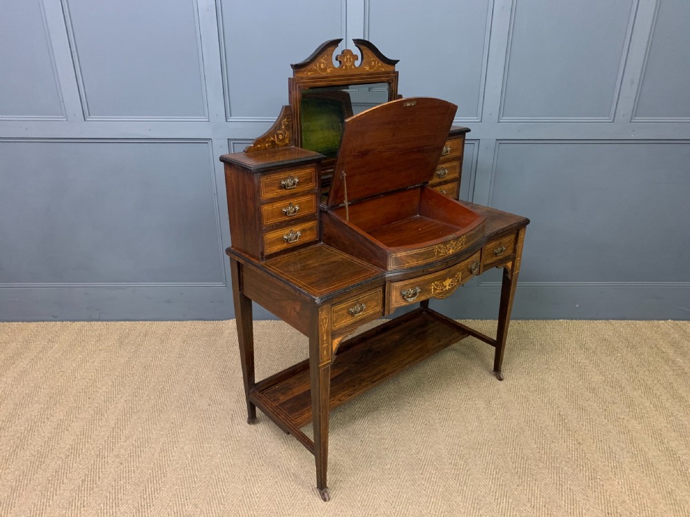An antique rosewood bonheur du jour writing desk featuring intricate marquetry inlays, a central mirror, green leather writing top, and tapered legs on brass castors. View XIV