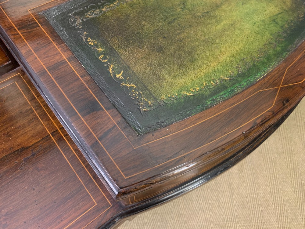 An antique rosewood bonheur du jour writing desk featuring intricate marquetry inlays, a central mirror, green leather writing top, and tapered legs on brass castors. View XVIII