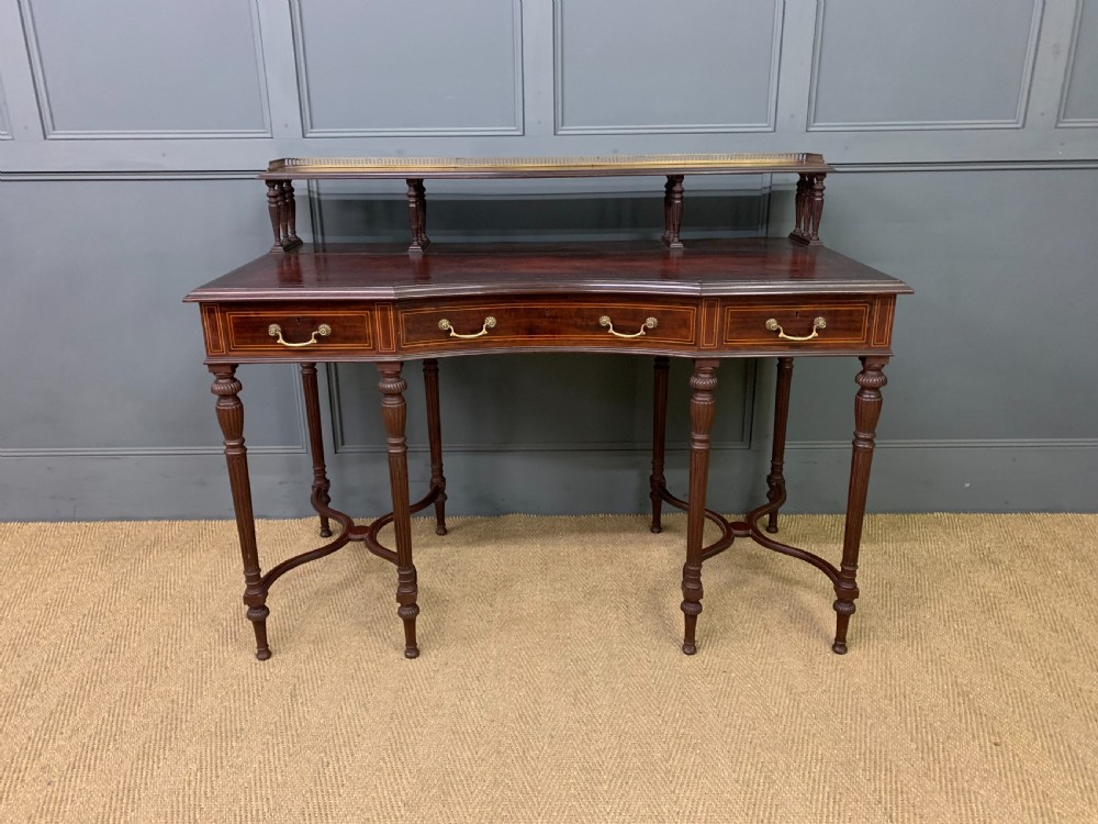 A late Victorian mahogany writing desk by Collinson and Lock with a raised upper shelf gallery, leather top, satinwood inlay, and turned legs. View II