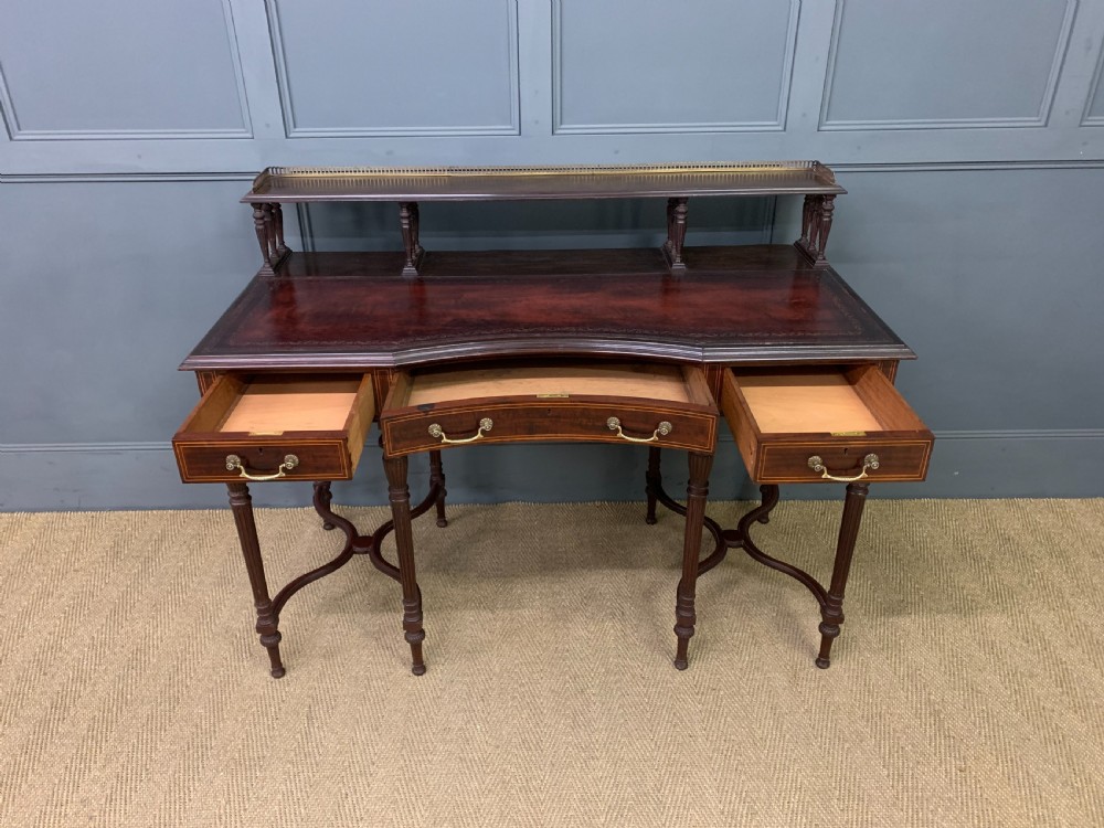 A late Victorian mahogany writing desk by Collinson and Lock with a raised upper shelf gallery, leather top, satinwood inlay, and turned legs. View IX