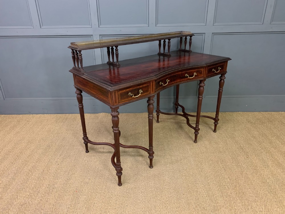 A late Victorian mahogany writing desk by Collinson and Lock with a raised upper shelf gallery, leather top, satinwood inlay, and turned legs. View X