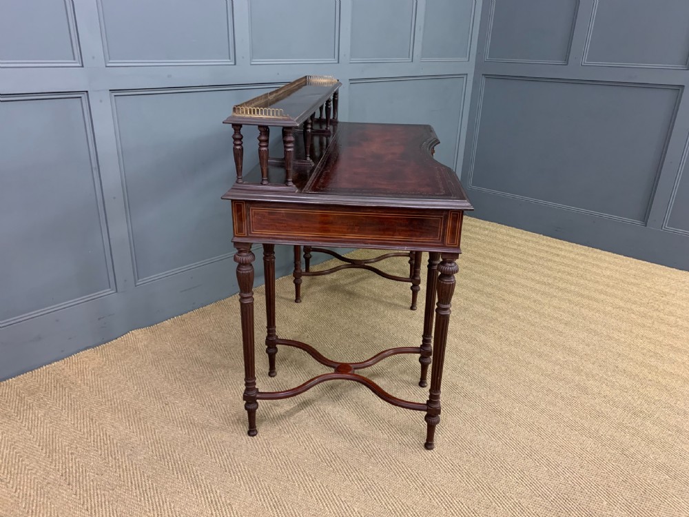 A late Victorian mahogany writing desk by Collinson and Lock with a raised upper shelf gallery, leather top, satinwood inlay, and turned legs. View XI