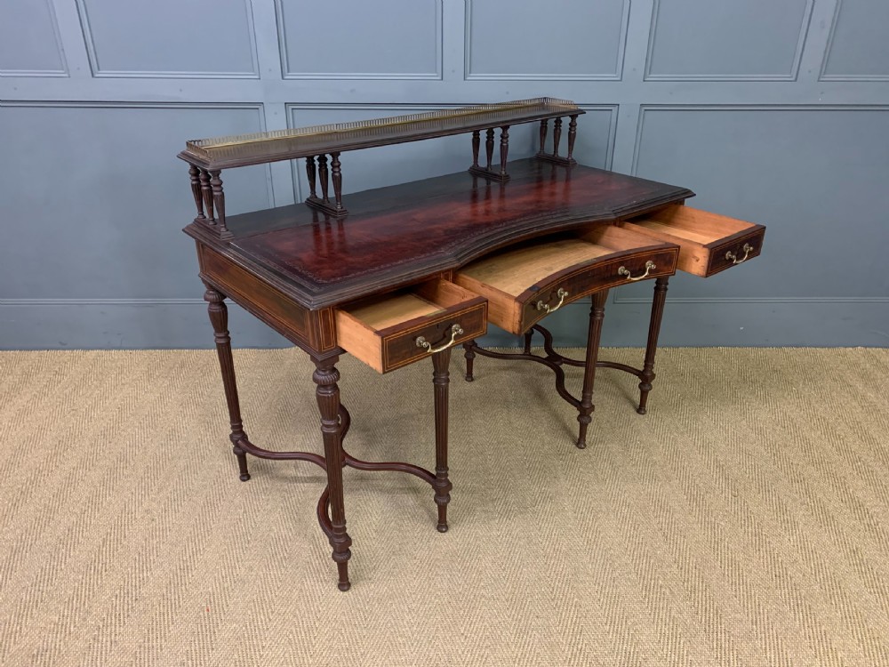 A late Victorian mahogany writing desk by Collinson and Lock with a raised upper shelf gallery, leather top, satinwood inlay, and turned legs. View XV