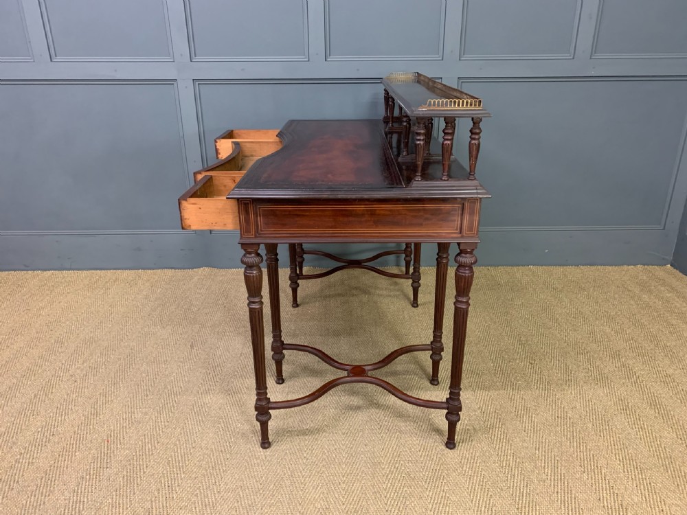 A late Victorian mahogany writing desk by Collinson and Lock with a raised upper shelf gallery, leather top, satinwood inlay, and turned legs. View XVII