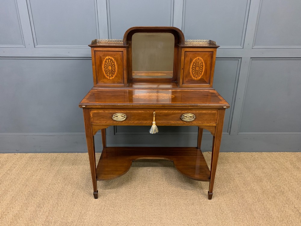 An Edwardian inlaid mahogany bonheur du jour writing desk featuring a central arched mirror, twin side cabinets with oval marquetry, brass galleries, and a lower shelf over tapered legs. View II