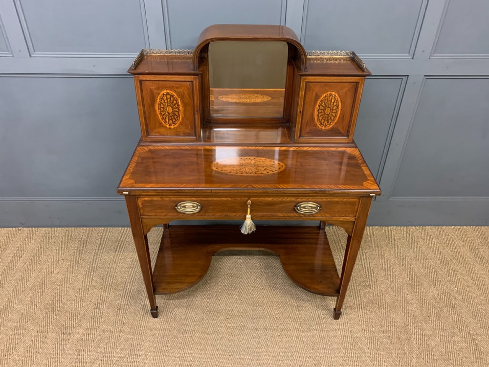 An Edwardian inlaid mahogany bonheur du jour writing desk featuring a central arched mirror, twin side cabinets with oval marquetry, brass galleries, and a lower shelf over tapered legs. View III