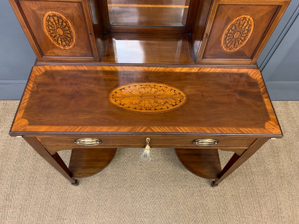 An Edwardian inlaid mahogany bonheur du jour writing desk featuring a central arched mirror, twin side cabinets with oval marquetry, brass galleries, and a lower shelf over tapered legs. View IX