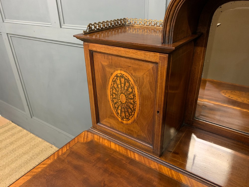 An Edwardian inlaid mahogany bonheur du jour writing desk featuring a central arched mirror, twin side cabinets with oval marquetry, brass galleries, and a lower shelf over tapered legs. View XI