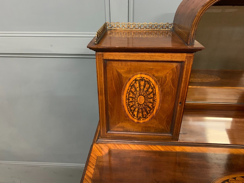 An Edwardian inlaid mahogany bonheur du jour writing desk featuring a central arched mirror, twin side cabinets with oval marquetry, brass galleries, and a lower shelf over tapered legs. View XII