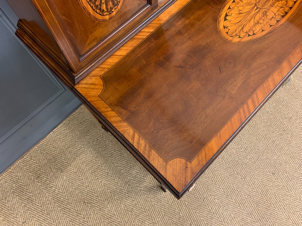 An Edwardian inlaid mahogany bonheur du jour writing desk featuring a central arched mirror, twin side cabinets with oval marquetry, brass galleries, and a lower shelf over tapered legs. View XV