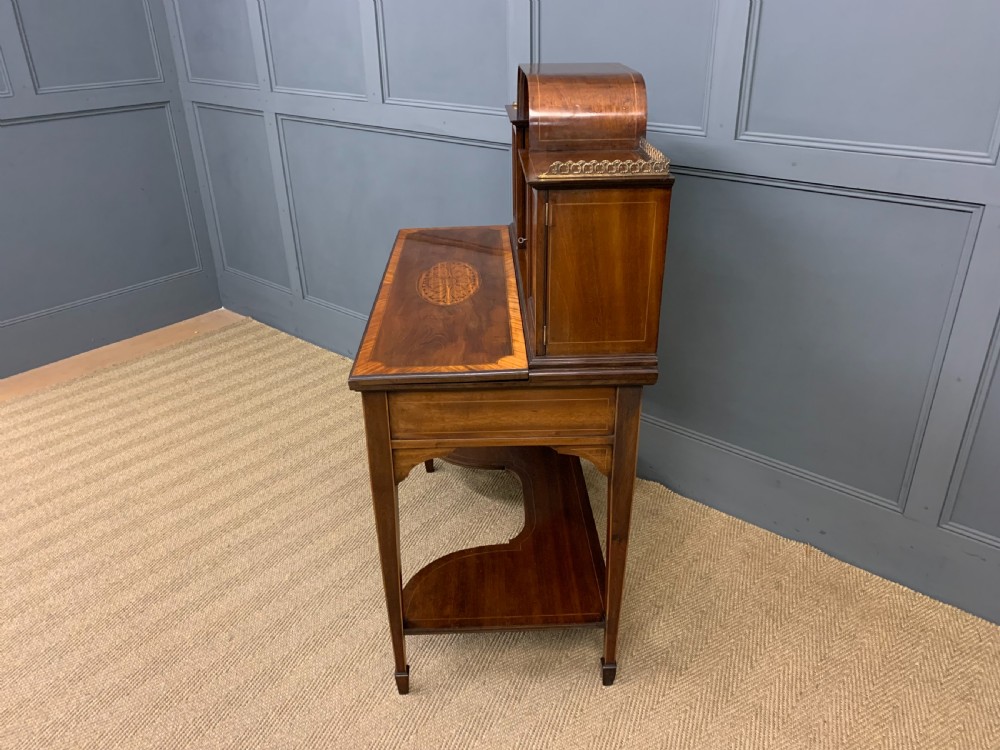 An Edwardian inlaid mahogany bonheur du jour writing desk featuring a central arched mirror, twin side cabinets with oval marquetry, brass galleries, and a lower shelf over tapered legs. View XIX