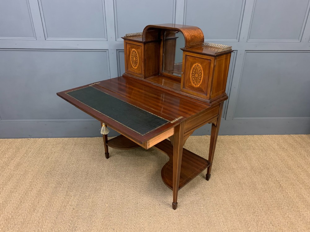 An Edwardian inlaid mahogany bonheur du jour writing desk featuring a central arched mirror, twin side cabinets with oval marquetry, brass galleries, and a lower shelf over tapered legs. View XXI