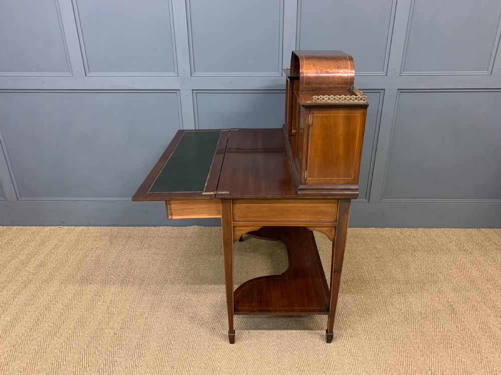 An Edwardian inlaid mahogany bonheur du jour writing desk featuring a central arched mirror, twin side cabinets with oval marquetry, brass galleries, and a lower shelf over tapered legs. View XXII
