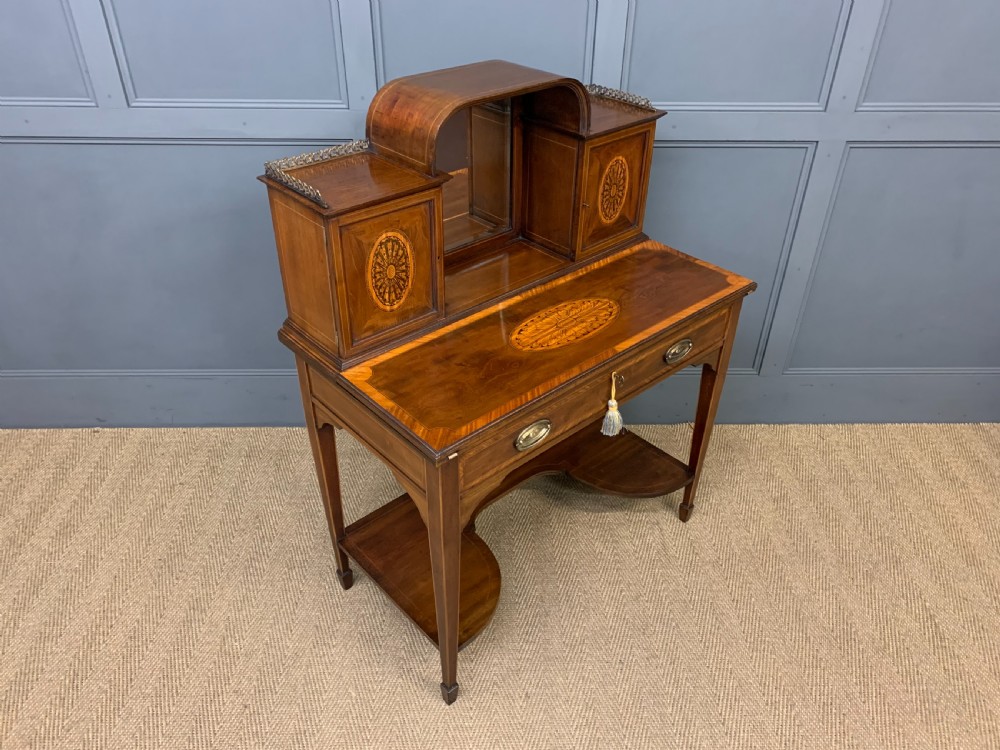An Edwardian inlaid mahogany bonheur du jour writing desk featuring a central arched mirror, twin side cabinets with oval marquetry, brass galleries, and a lower shelf over tapered legs. View XXIII