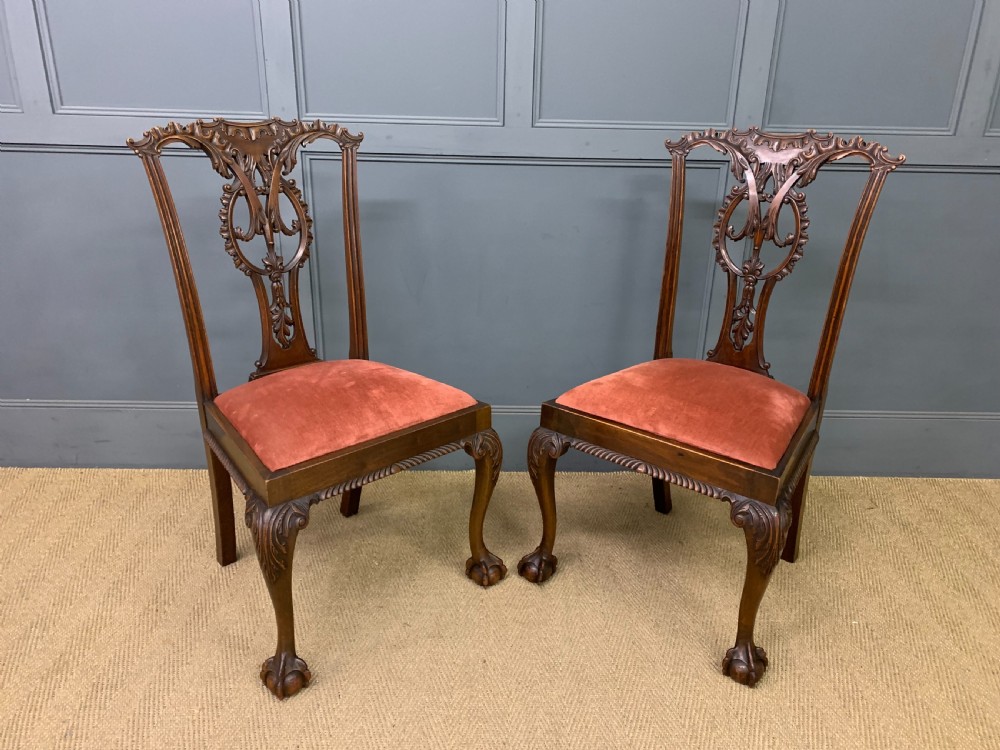 A pair of Chippendale style mahogany side chairs featuring intricate pierced back splats, cabriole legs with ball and claw feet, and terracotta velvet upholstered seats. View V