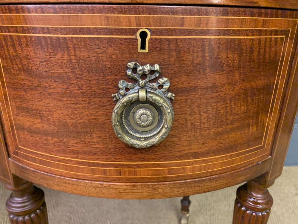 An Edwardian kidney-shaped mahogany writing desk featuring satinwood inlay, a leather writing surface, a brass gallery rail, and five drawers on fluted legs. View VII