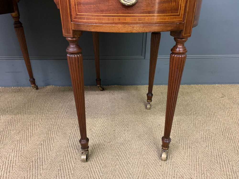 An Edwardian kidney-shaped mahogany writing desk featuring satinwood inlay, a leather writing surface, a brass gallery rail, and five drawers on fluted legs. View VIII