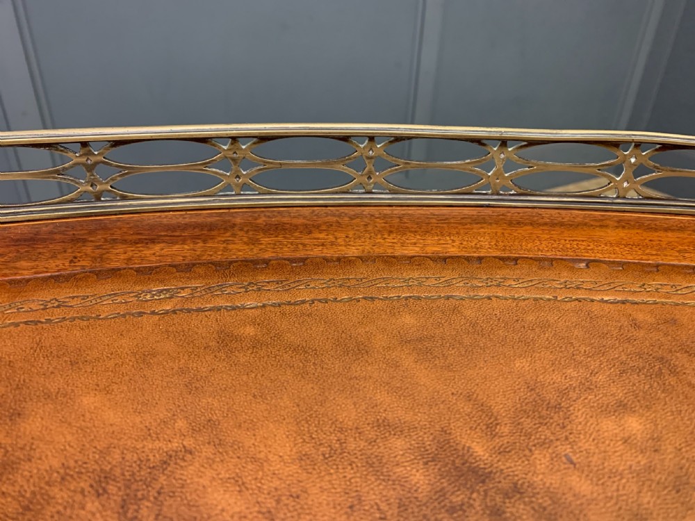 An Edwardian kidney-shaped mahogany writing desk featuring satinwood inlay, a leather writing surface, a brass gallery rail, and five drawers on fluted legs. View XVIII