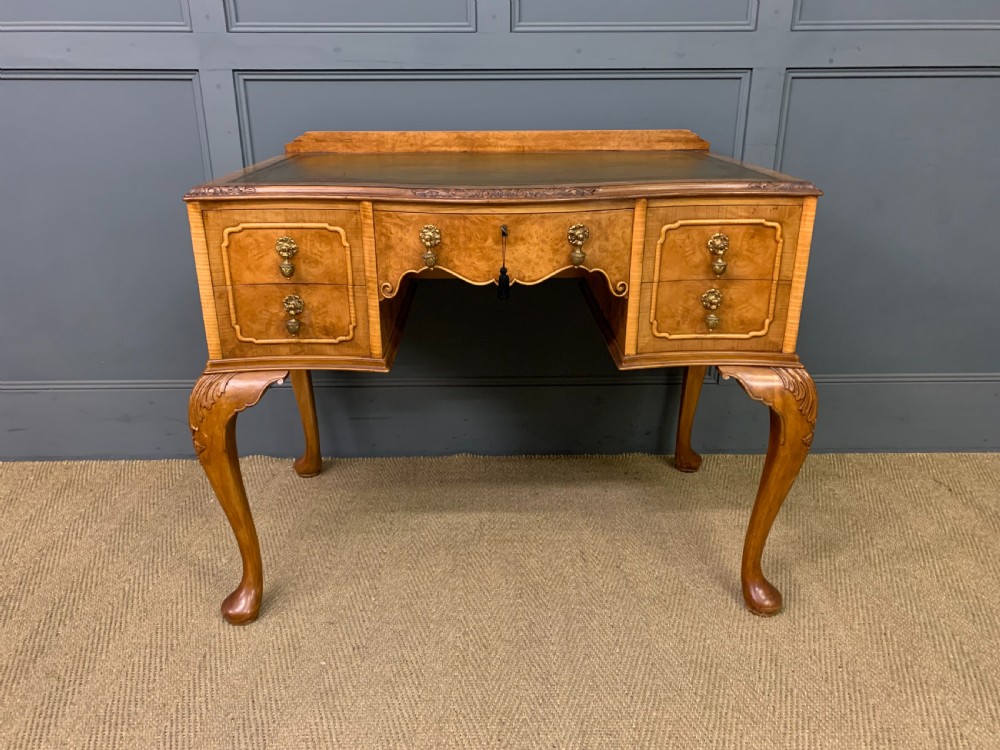A Queen Anne style burr walnut writing desk with an inset green leather surface, five drawers, brass drop pulls, and carved cabriole legs. View II