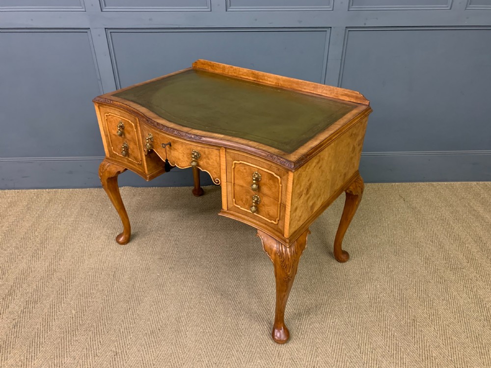 A Queen Anne style burr walnut writing desk with an inset green leather surface, five drawers, brass drop pulls, and carved cabriole legs. View XIII