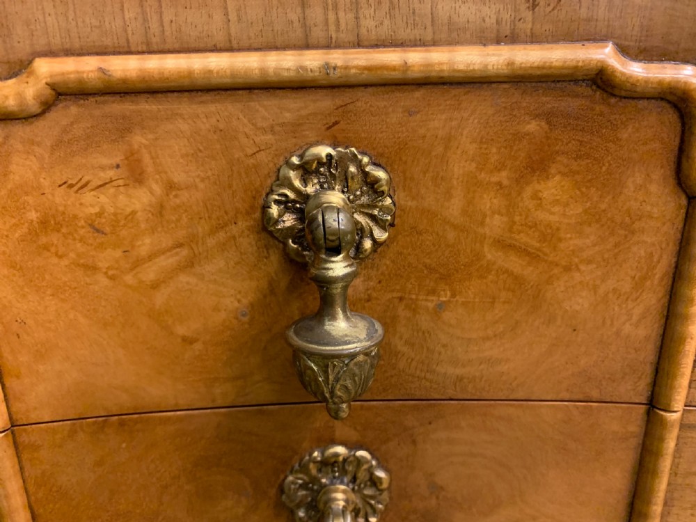 A Queen Anne style burr walnut writing desk with an inset green leather surface, five drawers, brass drop pulls, and carved cabriole legs. View XVII