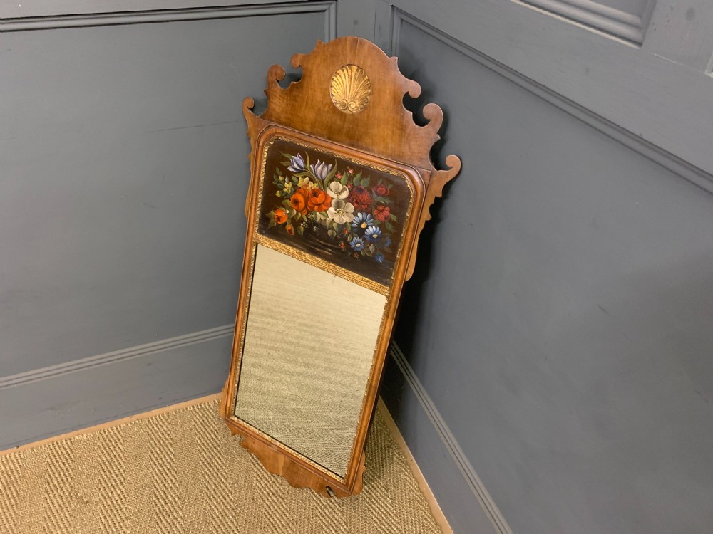 A vertical Queen Anne Revival walnut wall mirror featuring a scroll-cut frame, a gilded carved shell at the top crest, and a hand-painted floral still-life panel above the reflective mirror glass. View II