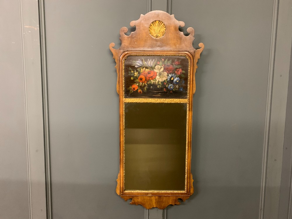 A vertical Queen Anne Revival walnut wall mirror featuring a scroll-cut frame, a gilded carved shell at the top crest, and a hand-painted floral still-life panel above the reflective mirror glass. View III