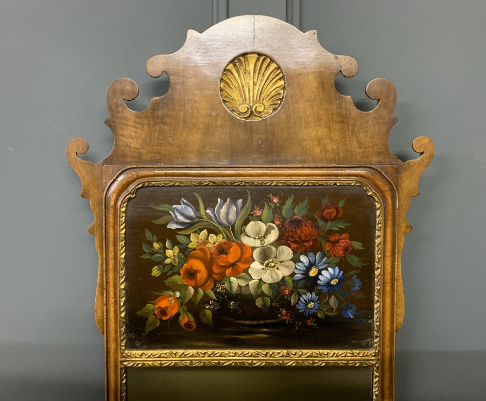 A vertical Queen Anne Revival walnut wall mirror featuring a scroll-cut frame, a gilded carved shell at the top crest, and a hand-painted floral still-life panel above the reflective mirror glass. View IV