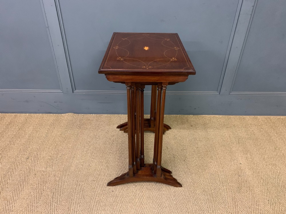 A set of four graduating mahogany nest of tables featuring satinwood line inlay and slender turned legs. View X